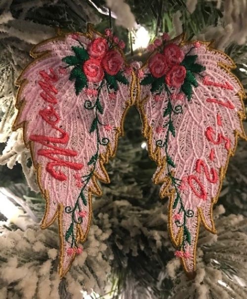 Decorative angel wings ornament with floral details on a Christmas tree.